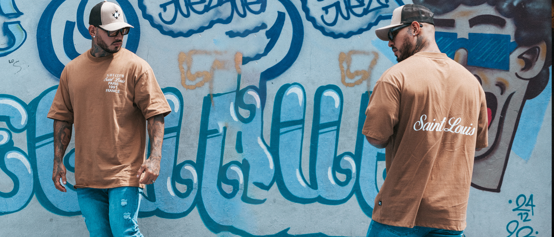 Hombres con camisetas oversize NAVI frente a un mural urbano